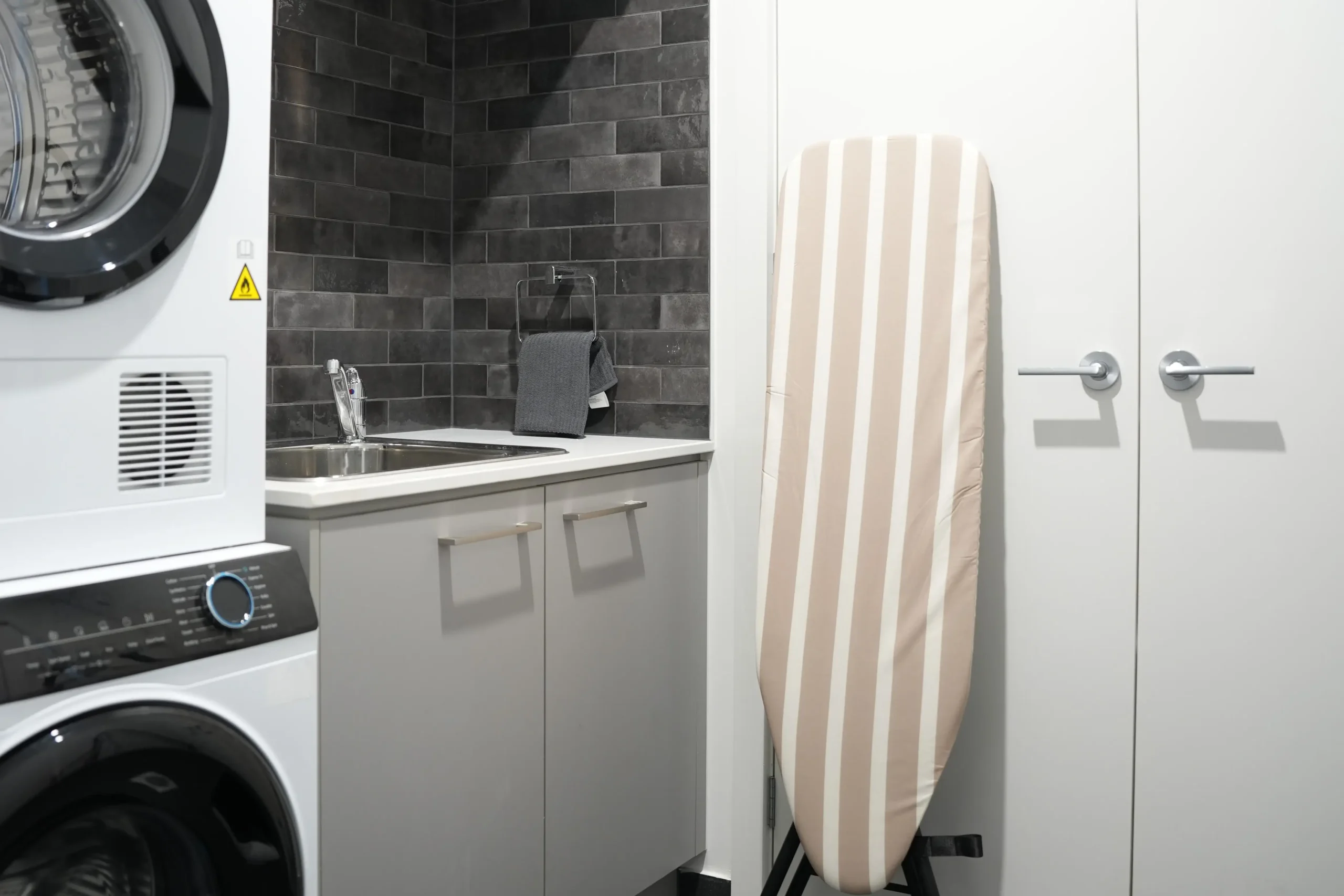 Greenbank Oasis internal laundry with full-size washing machine, dryer, ironing board and laundry sink — fully equipped for extended stays