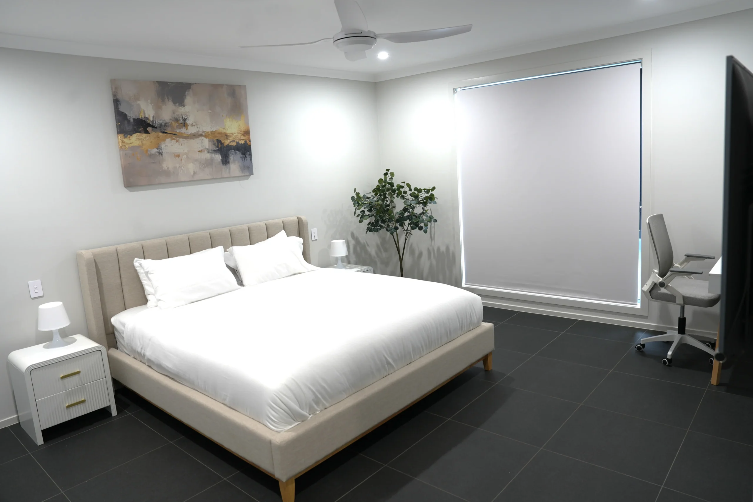 Greenbank Oasis master bedroom with king-size bed, wall-mounted smart television, dedicated work desk and ceiling fan — set up for extended stays