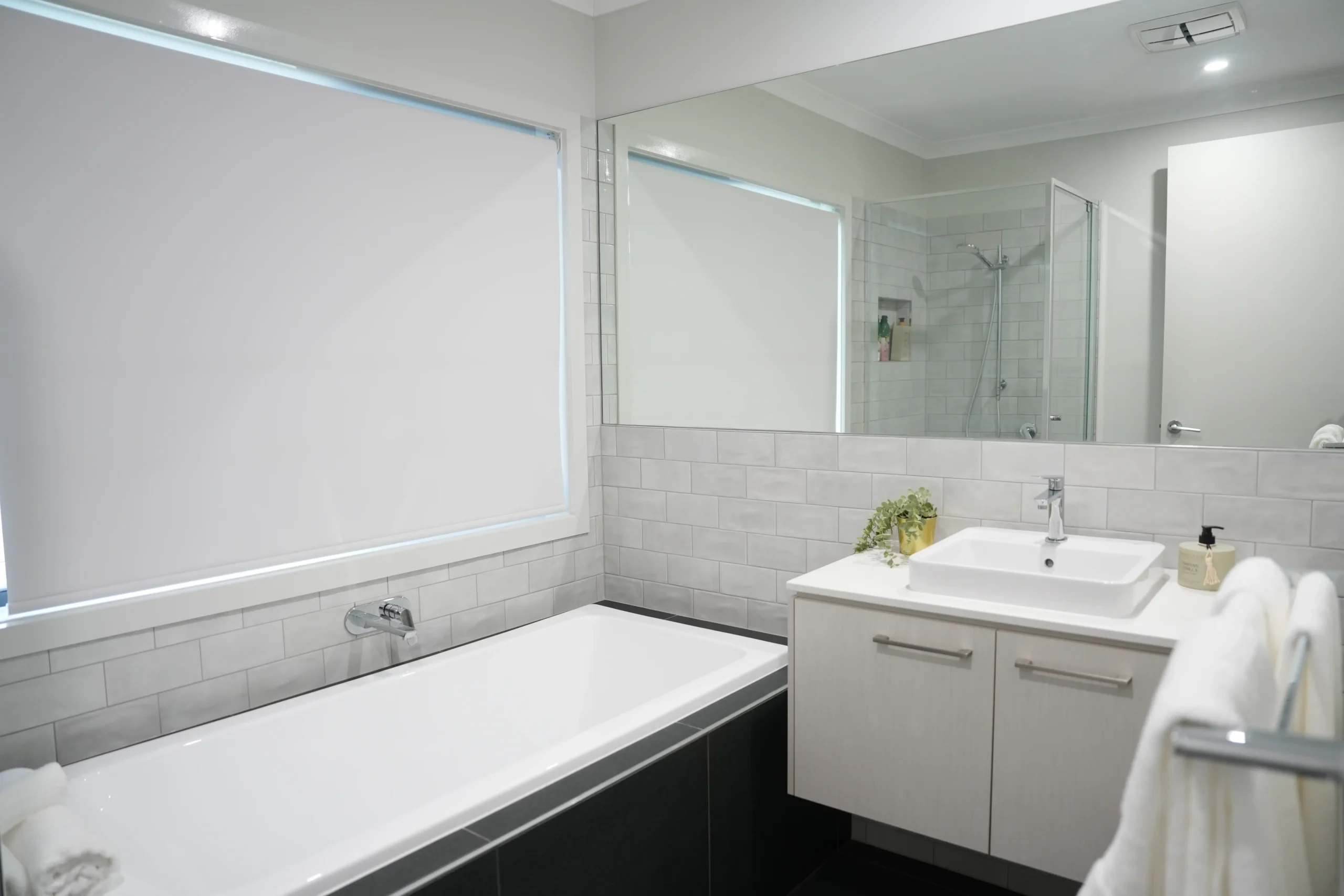 Modern family bathroom at Greenbank Oasis SafeStayz accommodation in Brisbane southside, with full-size bathtub, walk-in shower, vanity and fresh towels
