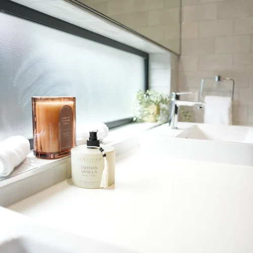 Bathroom vanity detail at Greenbank Oasis SafeStayz accommodation in Brisbane southside, with fresh towels, scented candle and quality hand soap provided for guests